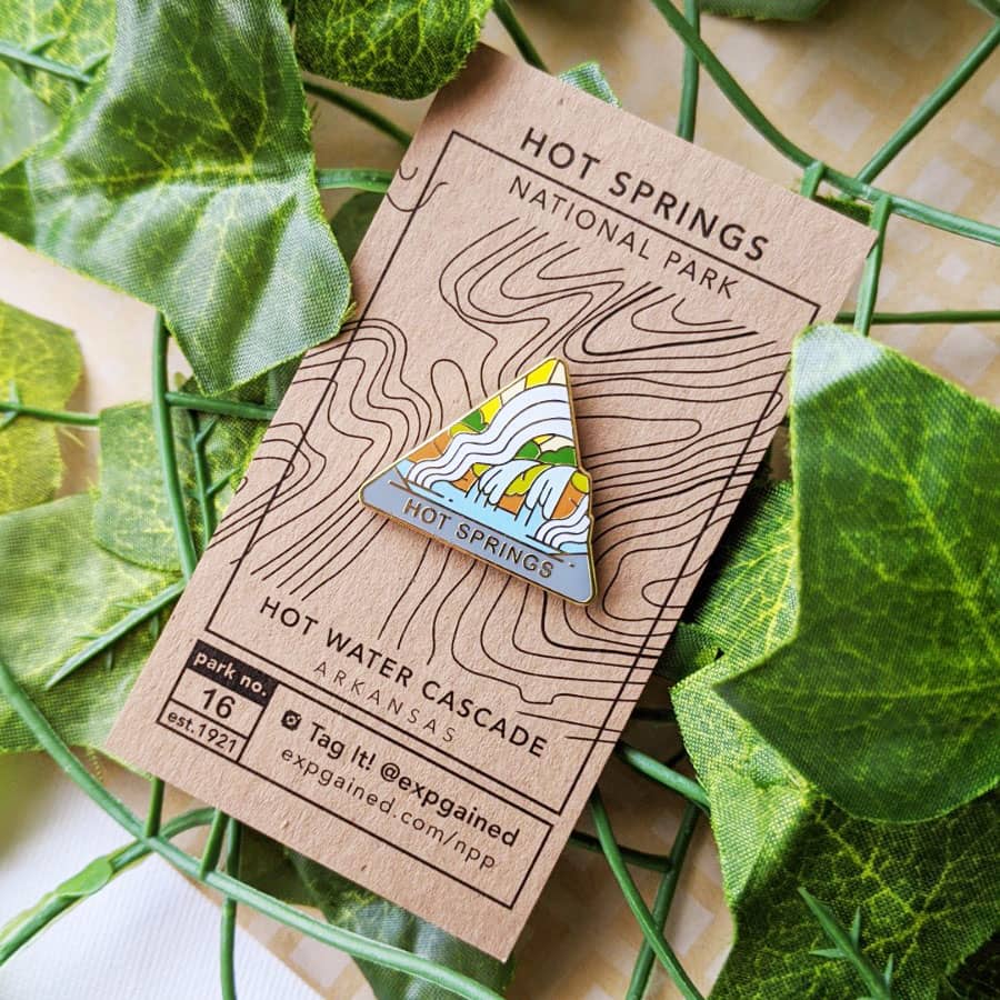 Triangle Hot Springs national park enamel pin featuring a view from the beehive hike on a brown business card size backing card with a topo map of the hot water cascadee.