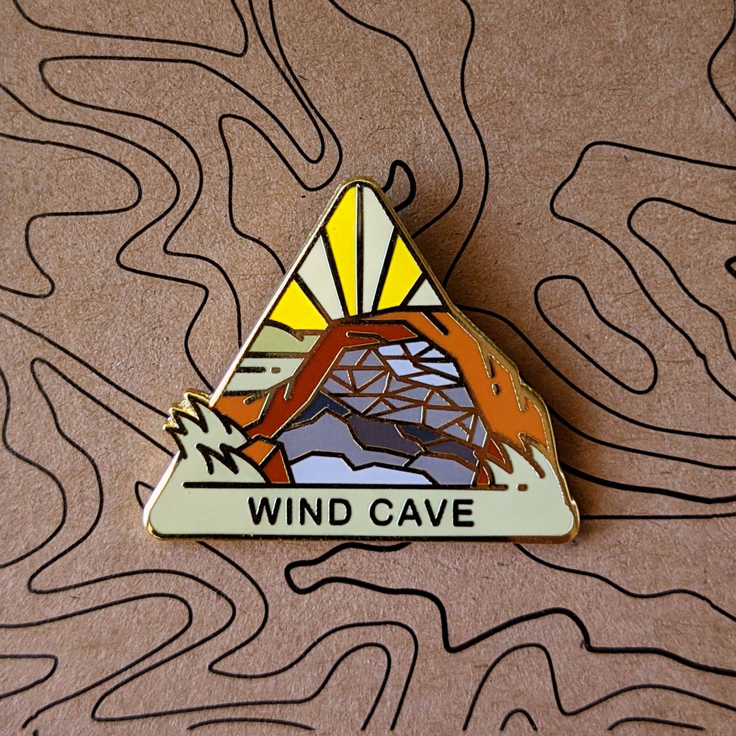 Triangle Wind Cave national park enamel pin featuring a view of honeycomb formations in a cave.