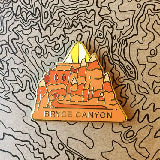Triangle Bryce Canyon national park enamel pin featuring a view of hoodoos along the Queen's Garden.