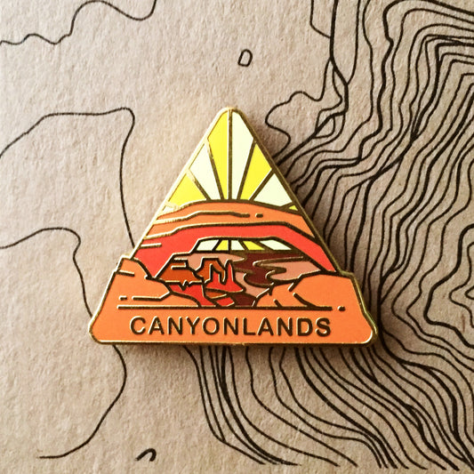 Triangle Canyonlands national park enamel pin featuring a view of Mesa Arch.