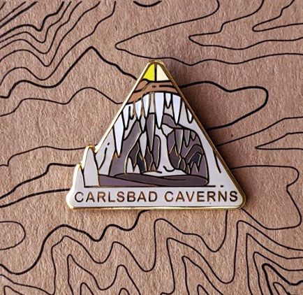 Triangle Carlsbad Caverns national park enamel pin featuring a view of giant calcite and stalactite formations.