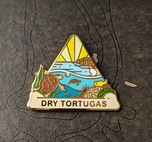 Triangle Dry Tortugas national park enamel pin featuring a view of underwater life and the coastal Fort Jefferson in the distance.