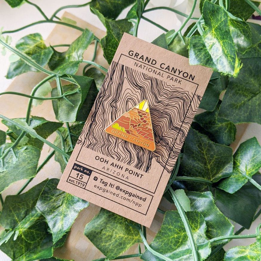 Triangle Grand Canyon national park enamel pin featuring a view from the beehive hike on a brown business card size backing card with a topo map of Ooh Aah Point..