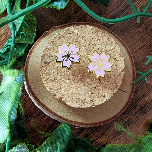Pink floral cherry blossom sakura earring studs on a cork coaster with greenery around