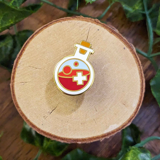 red health potion with a white cross in a bottle enamel pin