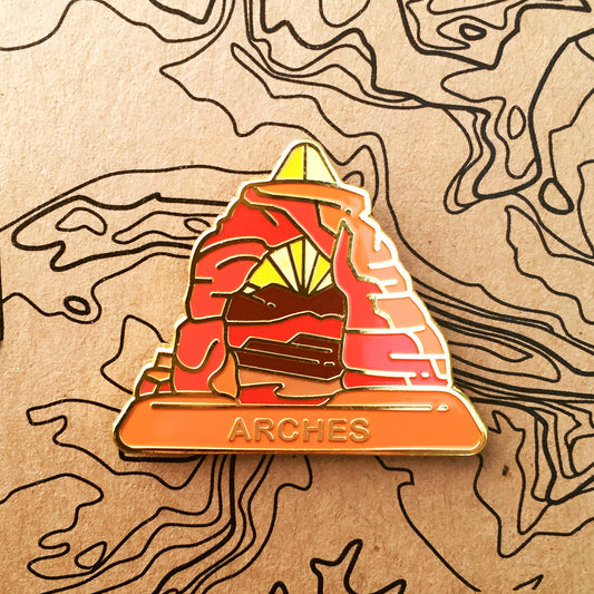 Triangle Arches national park enamel pin featuring a view of the Delicate Arch.