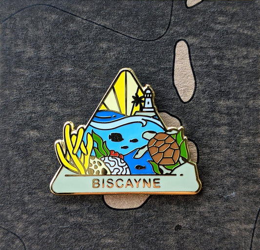 Triangle Biscayne national park enamel pin featuring a view of underwater life and the Boca Chita lighthouse in the distance.