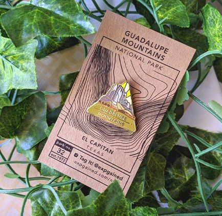 Triangle Guadalupe Mountains national park enamel pin featuring a view from the beehive hike on a brown business card size backing card with a topo map of El Capitan's location.