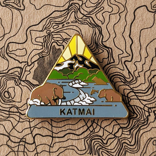 Triangle Katmai national park enamel pin featuring a view of bears catching fish with mount katmai in the backgroun.