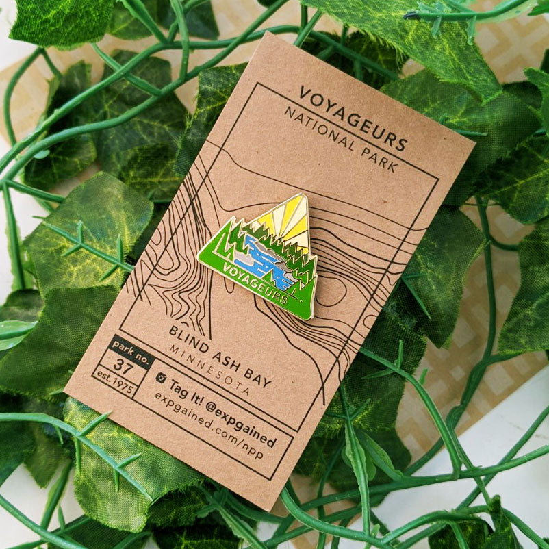 Triangle Voyageurs national park enamel pin featuring a view from the beehive hike on a brown business card size backing card with a topo map of Blind Ash Bay.